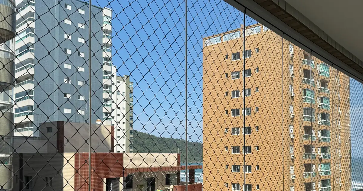 Balcón de un departamento en altura con malla de seguridad frente a otros edificios