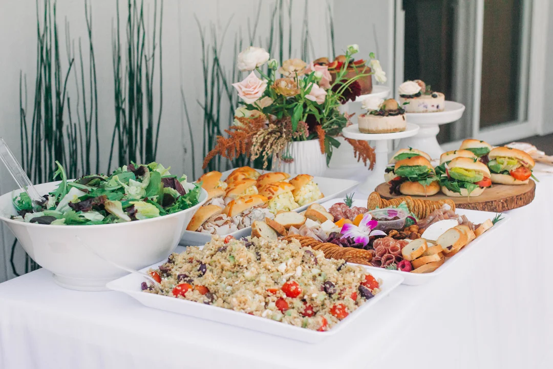 Baby shower grazing table with salads, sandwiches, fruit, and pastries