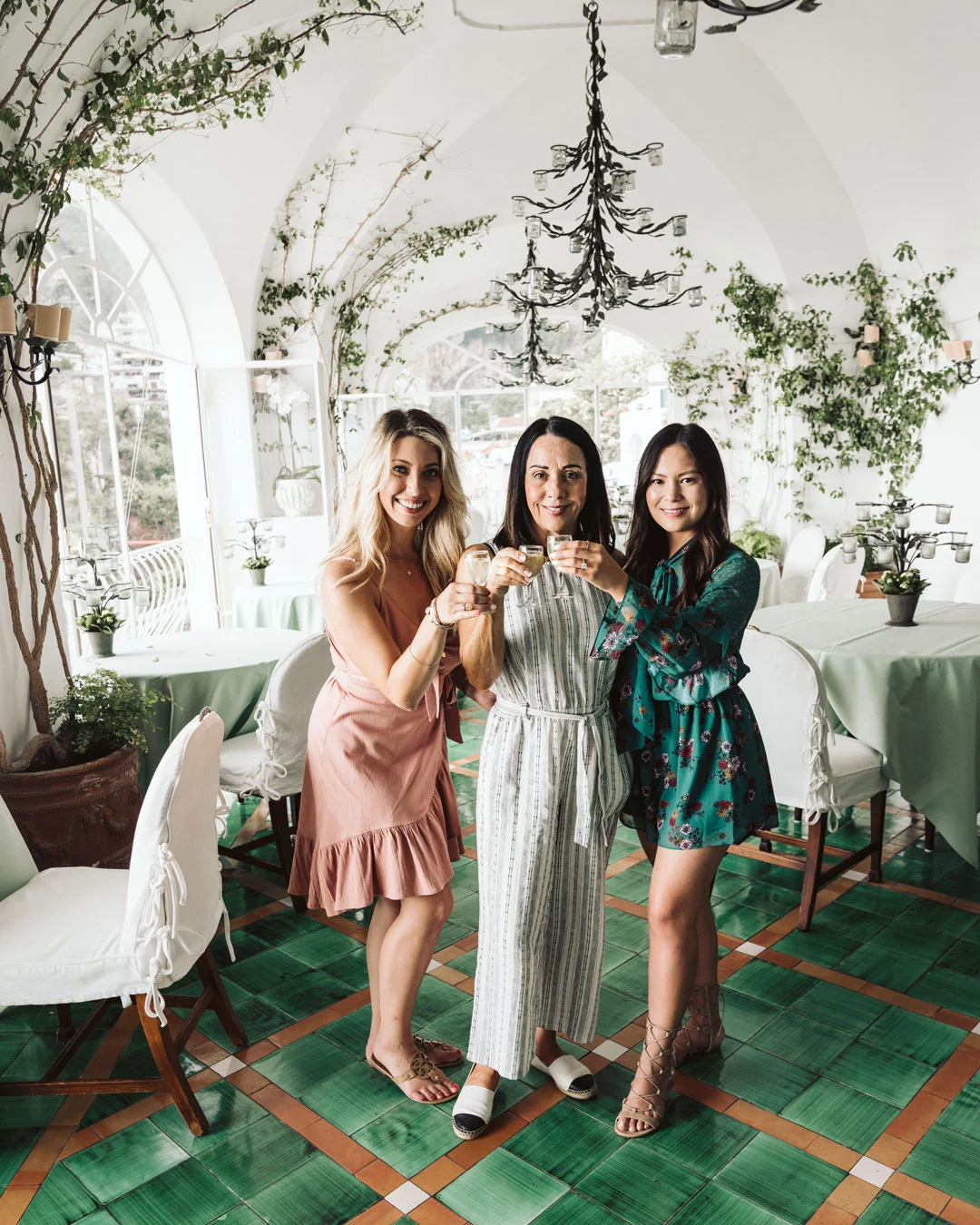 Three women raising glasses in an ornate dining room