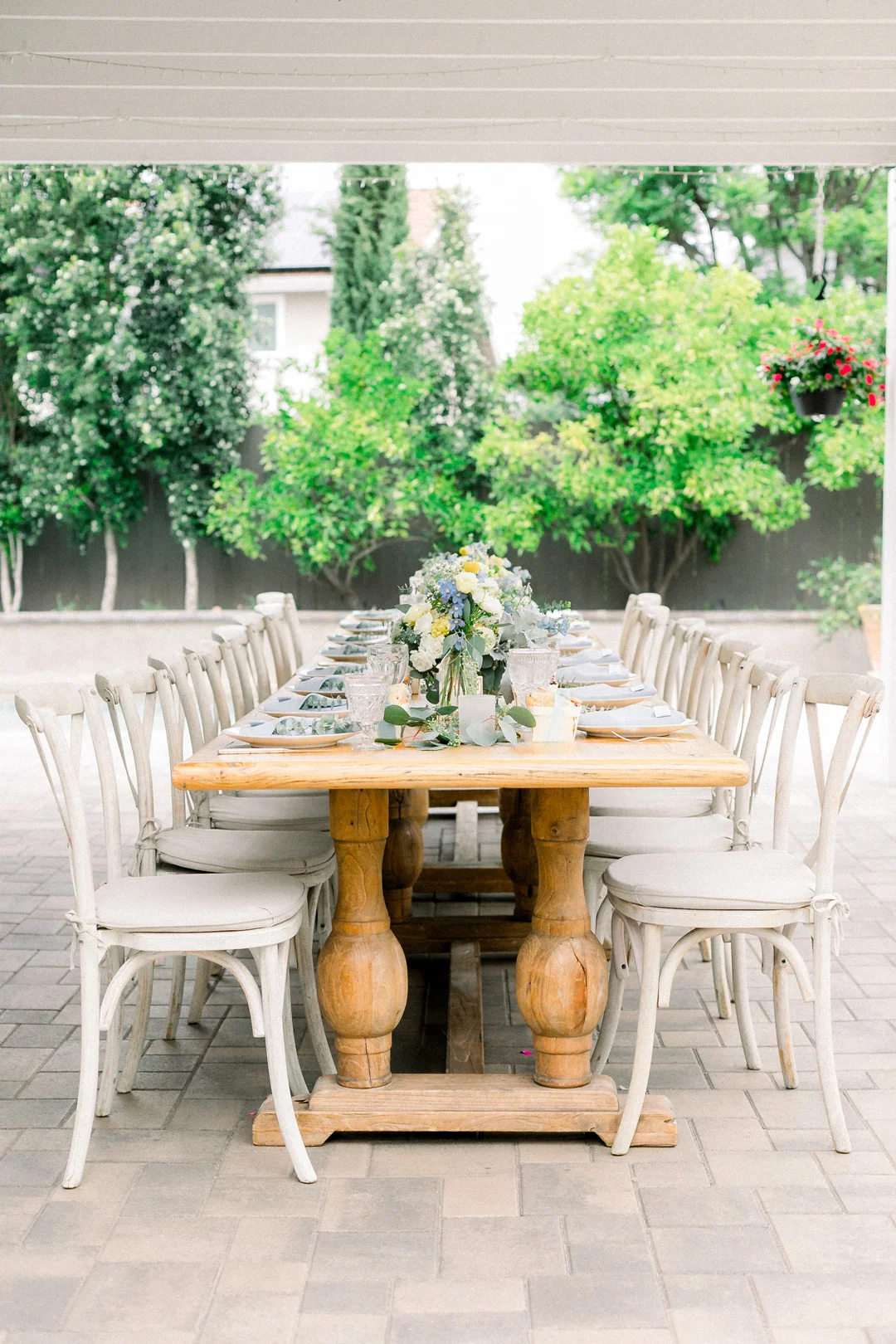 Long baby shower table with white chairs and floral centerpieces
