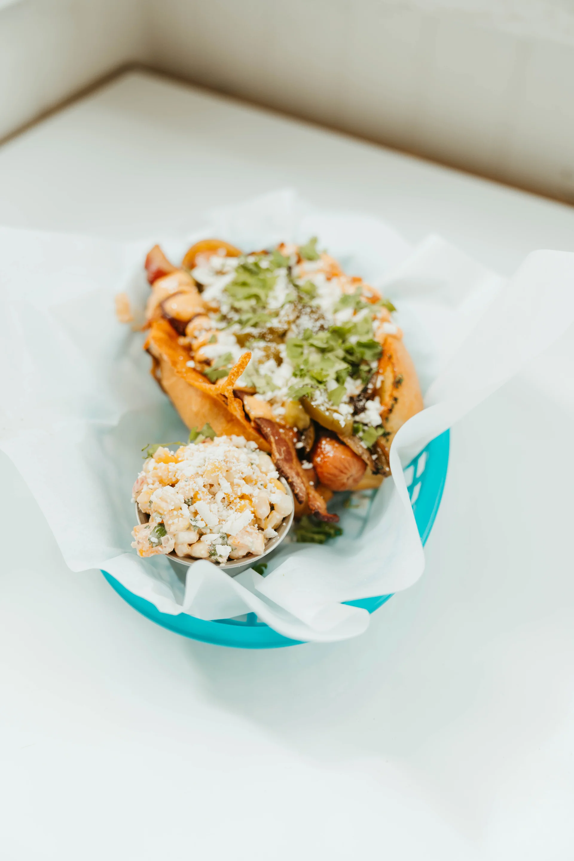 Summer Dog topped with peppers, chipotle aioli, cotija, and cilantro