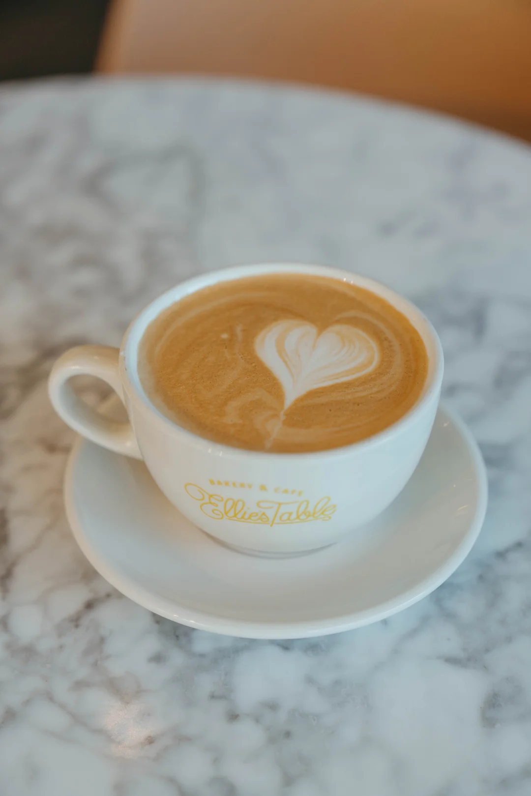 Hot latte with heart foam art in an Ellie’s Table cup