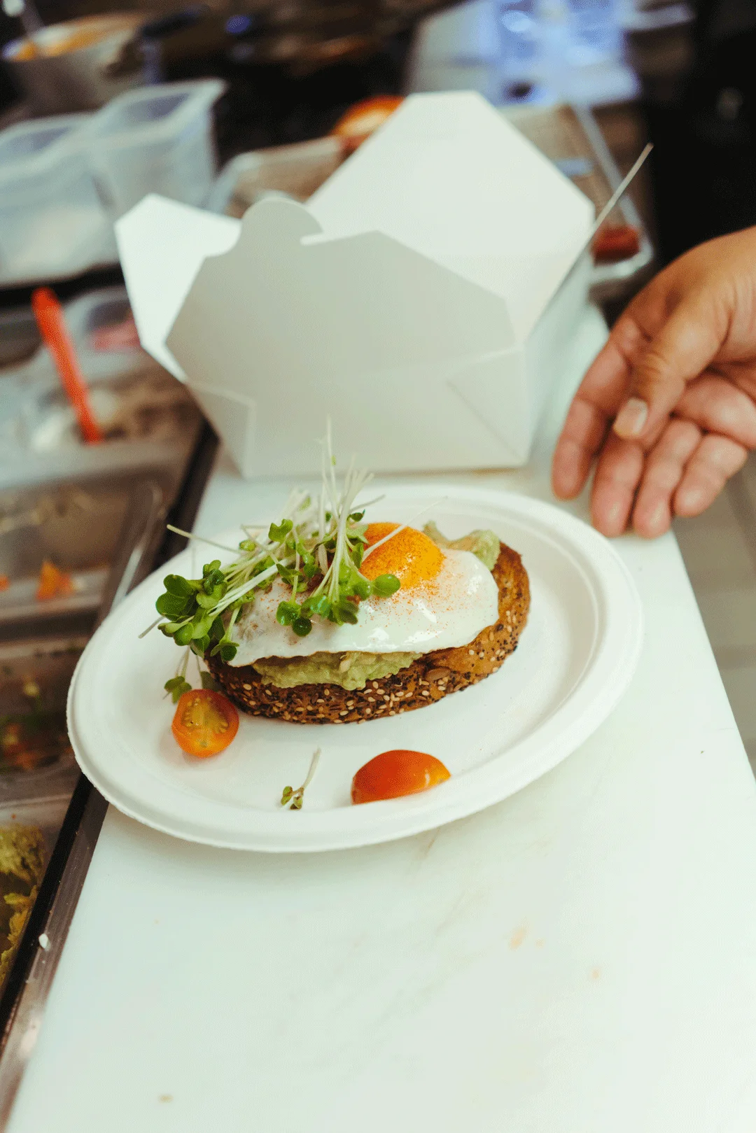 Chef Ken placing an egg-topped toast into a takeout box