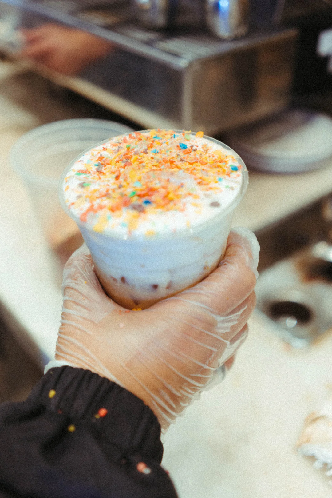 Iced Rainbow Latte topped with foam and colorful sprinkles