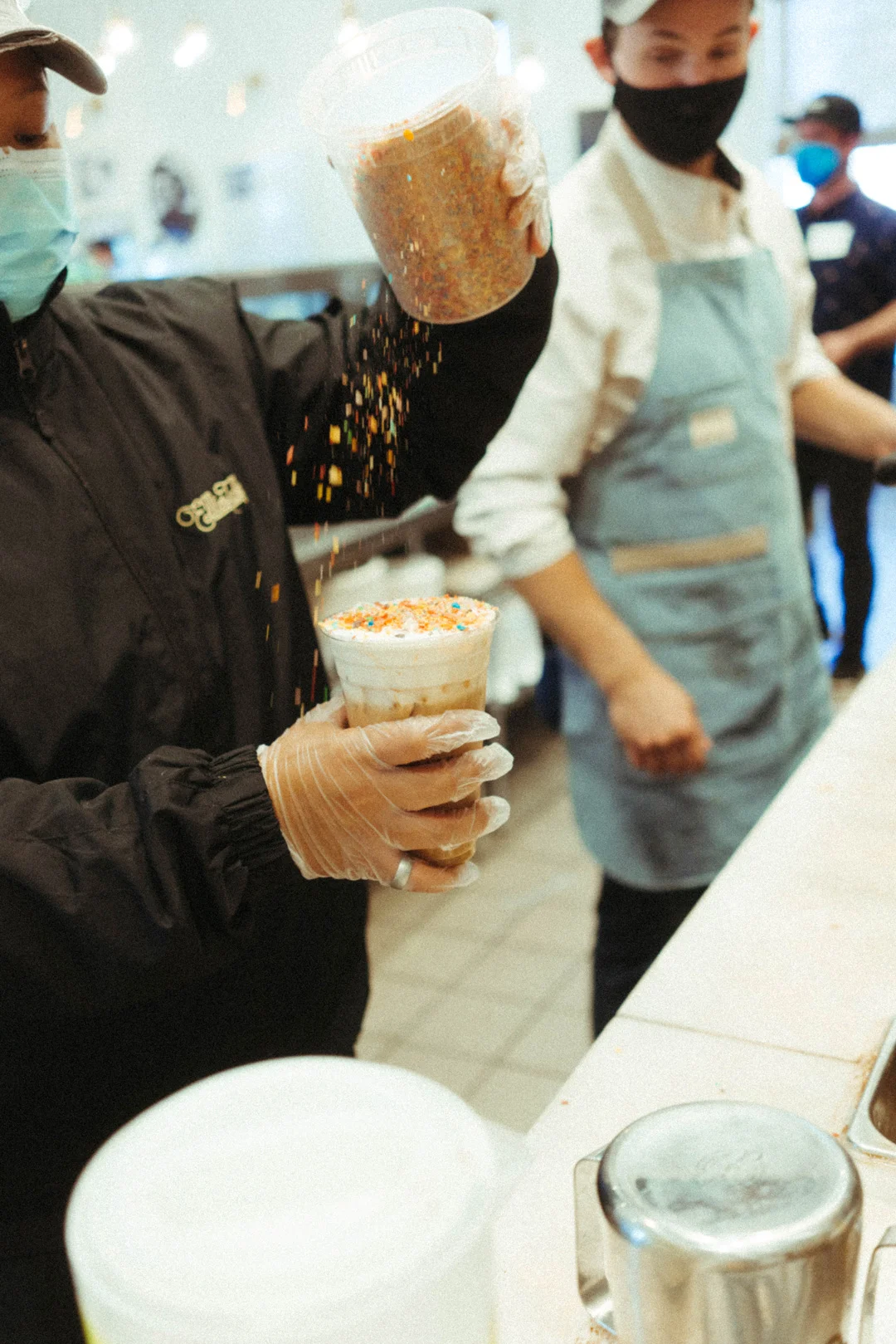 Leena adding rainbow sprinkles to an iced latte