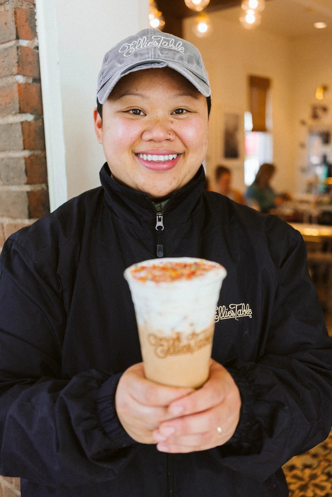 Leena holding an Iced Rainbow Latte inside Ellie’s Table