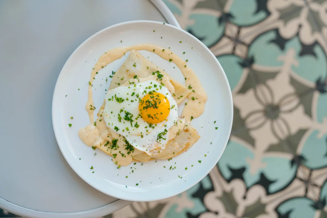 Prosciutto brie crepe topped with a fried egg and herbs