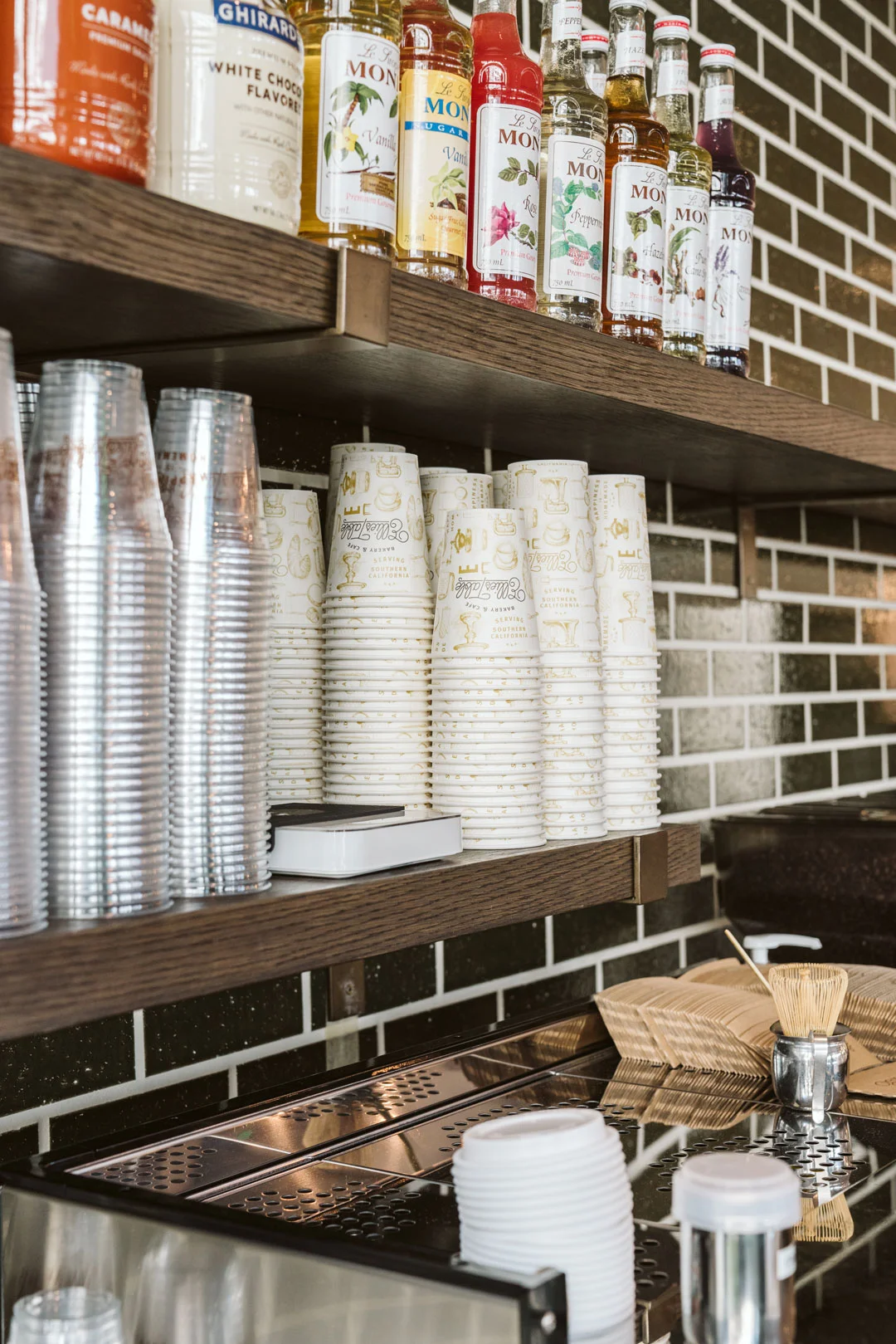 Coffee syrups, cups, and supplies on shelves above the café station