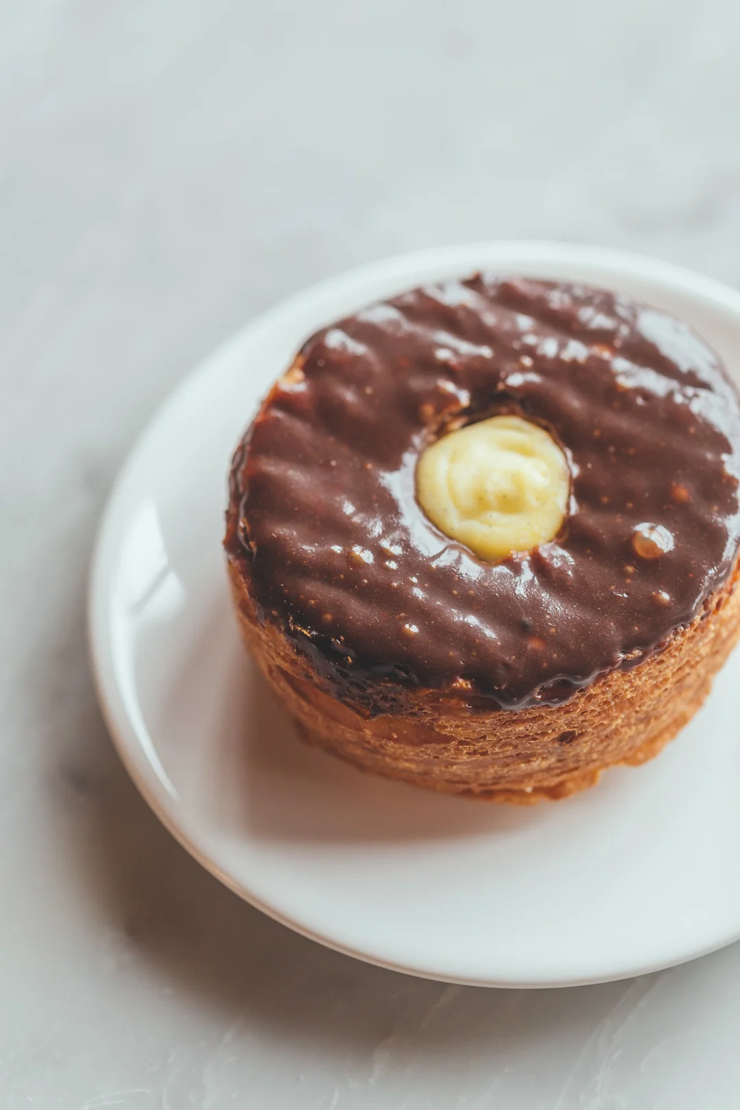 Round chocolate-glazed pastry on a white plate