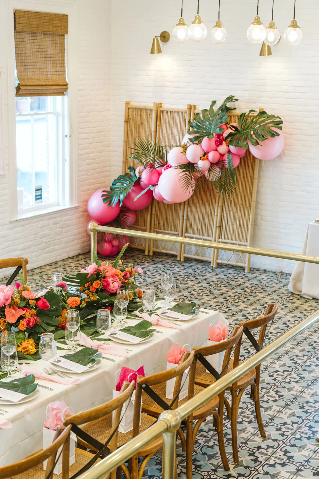 Dinner table set with tropical greenery and bright flowers