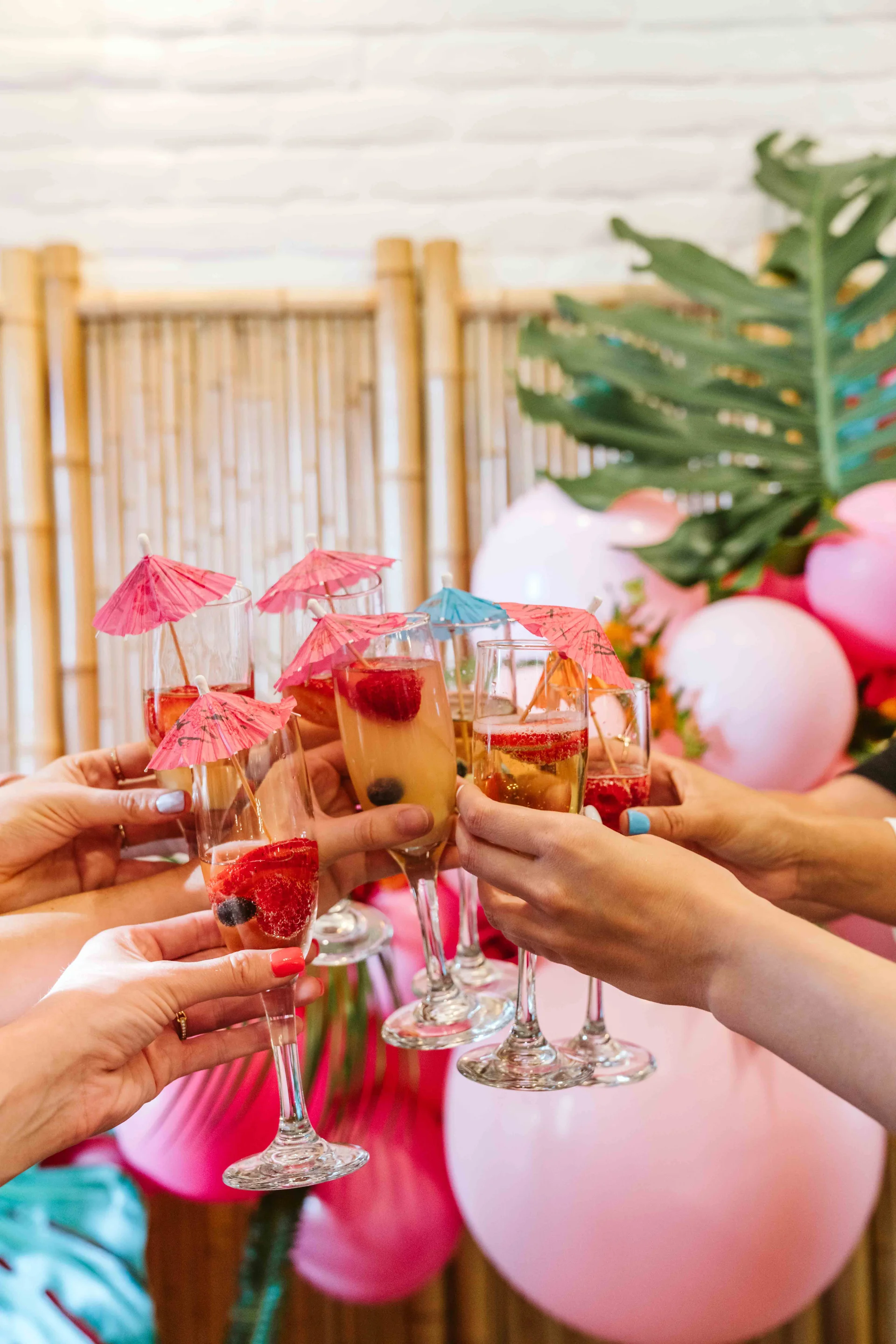Guests clinking glasses beside the pink balloon display