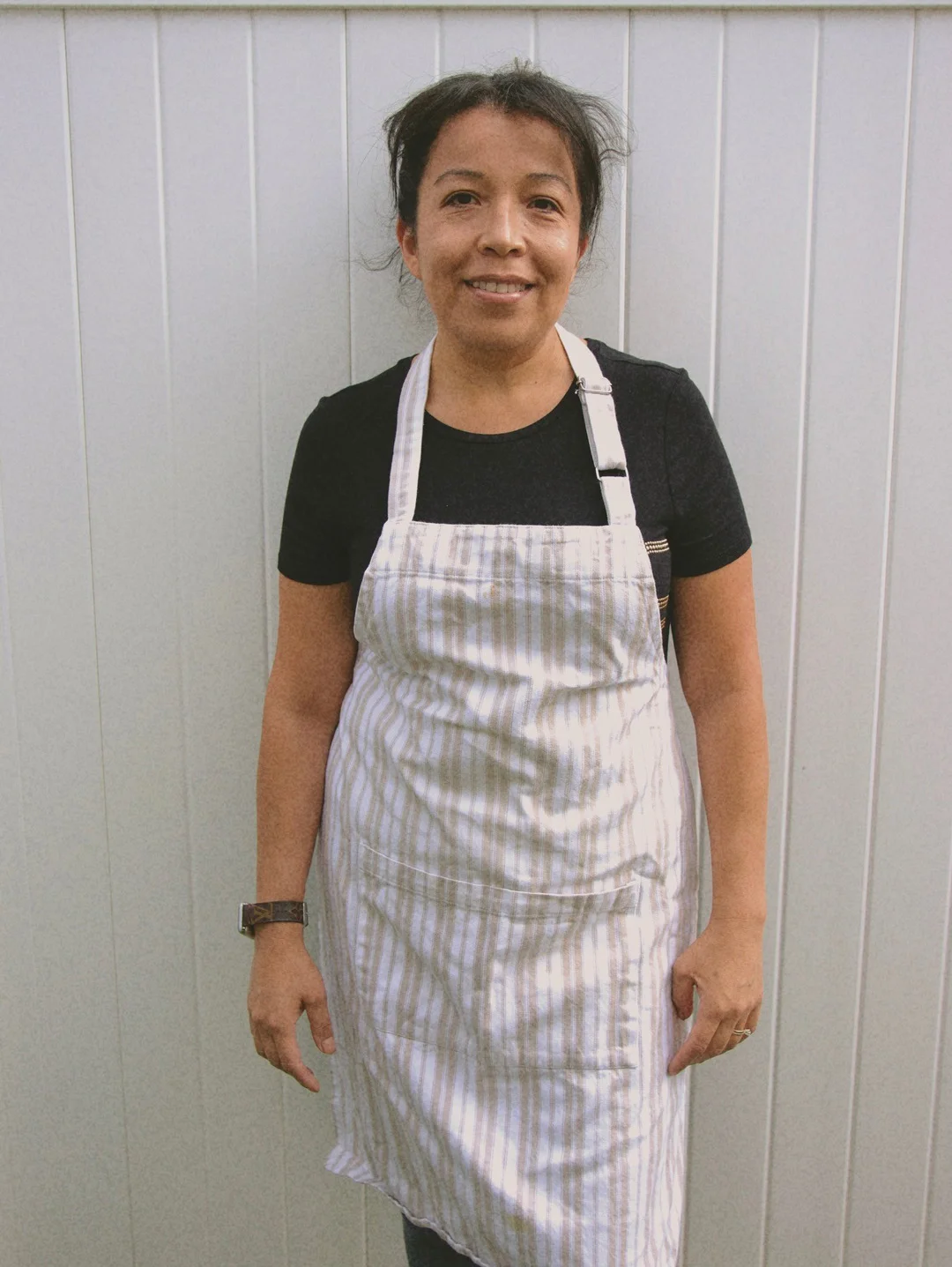 Claudia wearing a striped apron outside the café