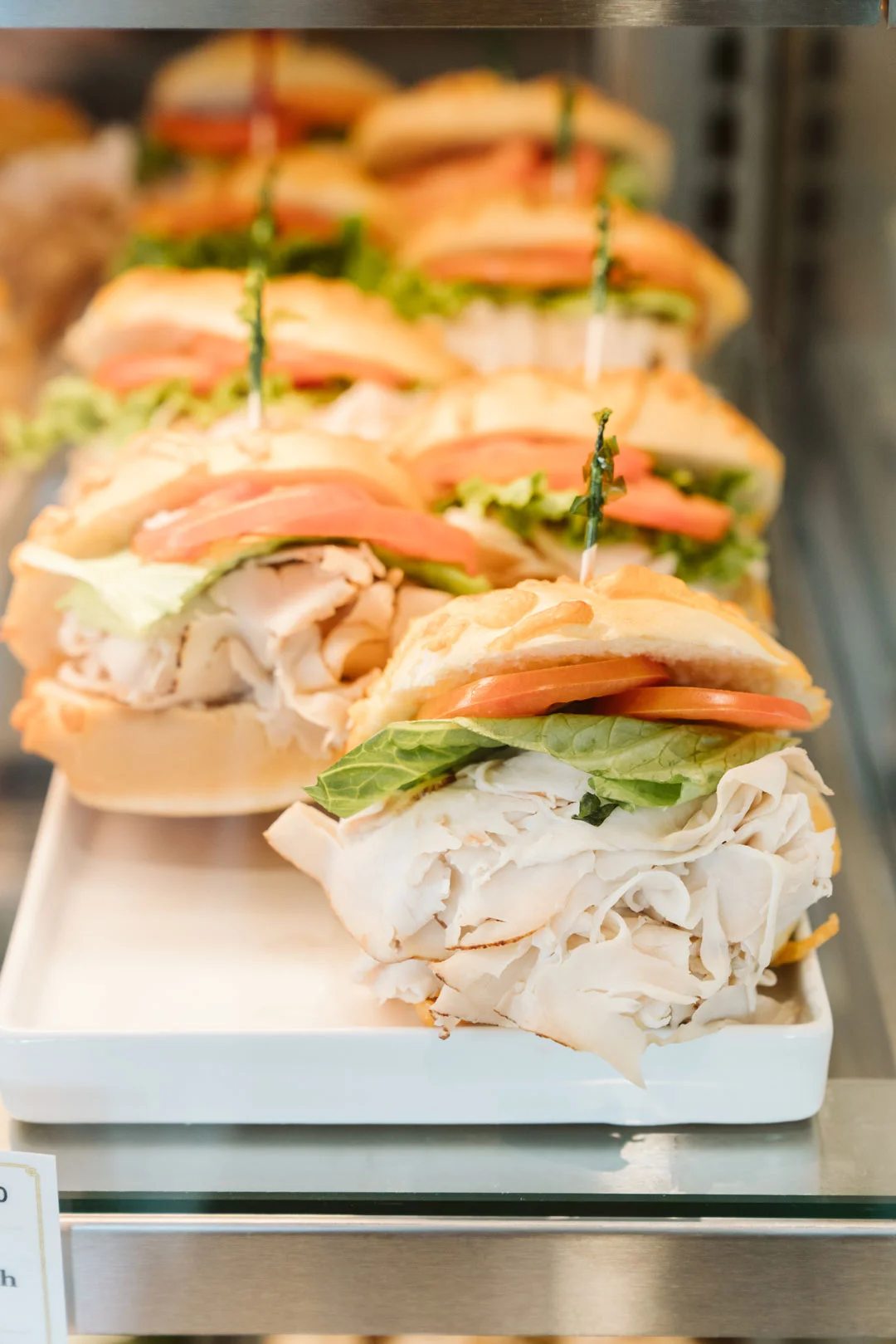 Turkey, tomato, and lettuce sandwiches stacked in the display case