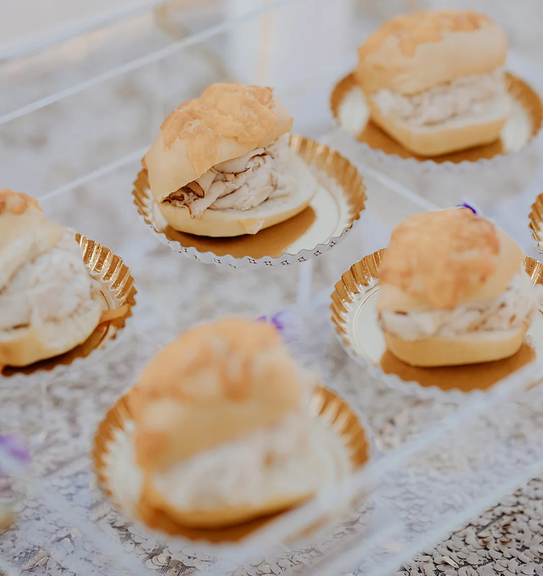 Small turkey sandwiches on cheese rolls arranged on a tray