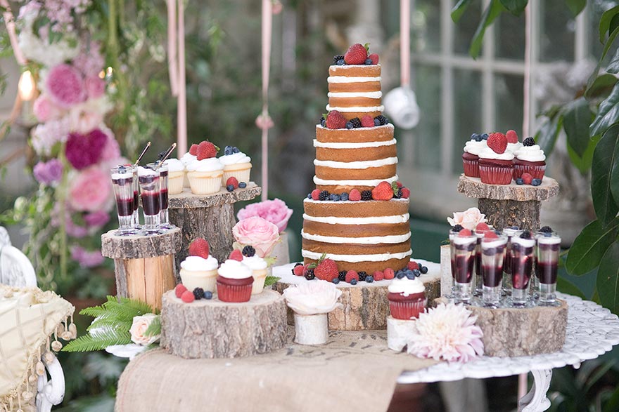 Berry-topped naked wedding cake with cupcakes and dessert shots