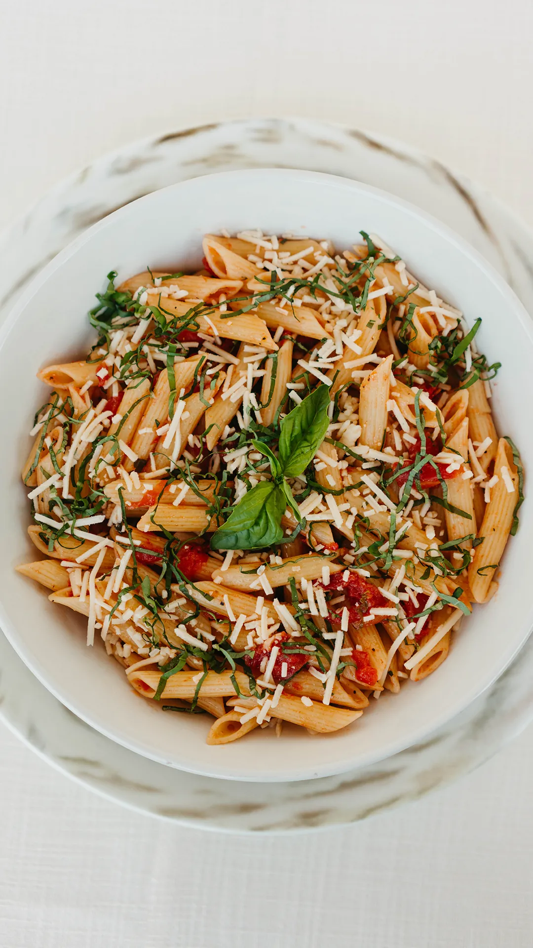 Penne alla checca with tomatoes, basil, and shredded cheese in a buffet chafing dish
