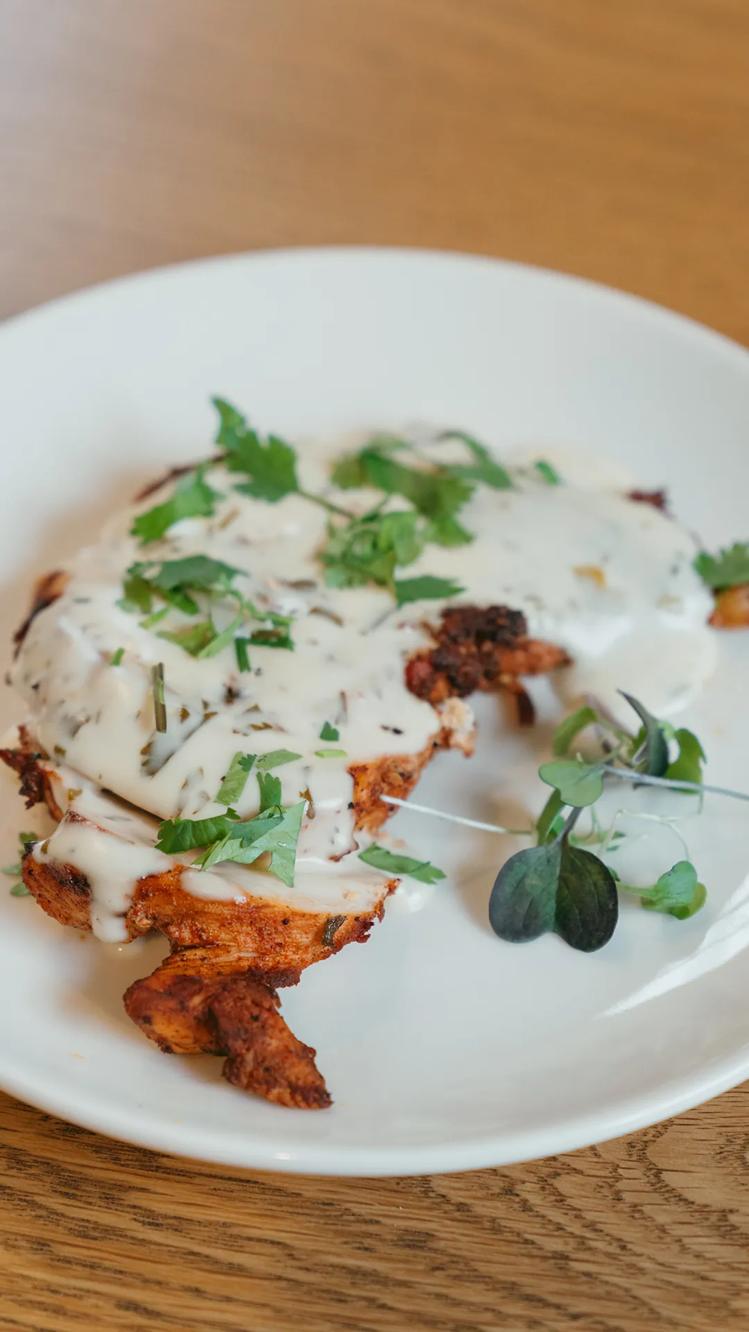 Tequila lime chicken with cream sauce and microgreens on a white plate