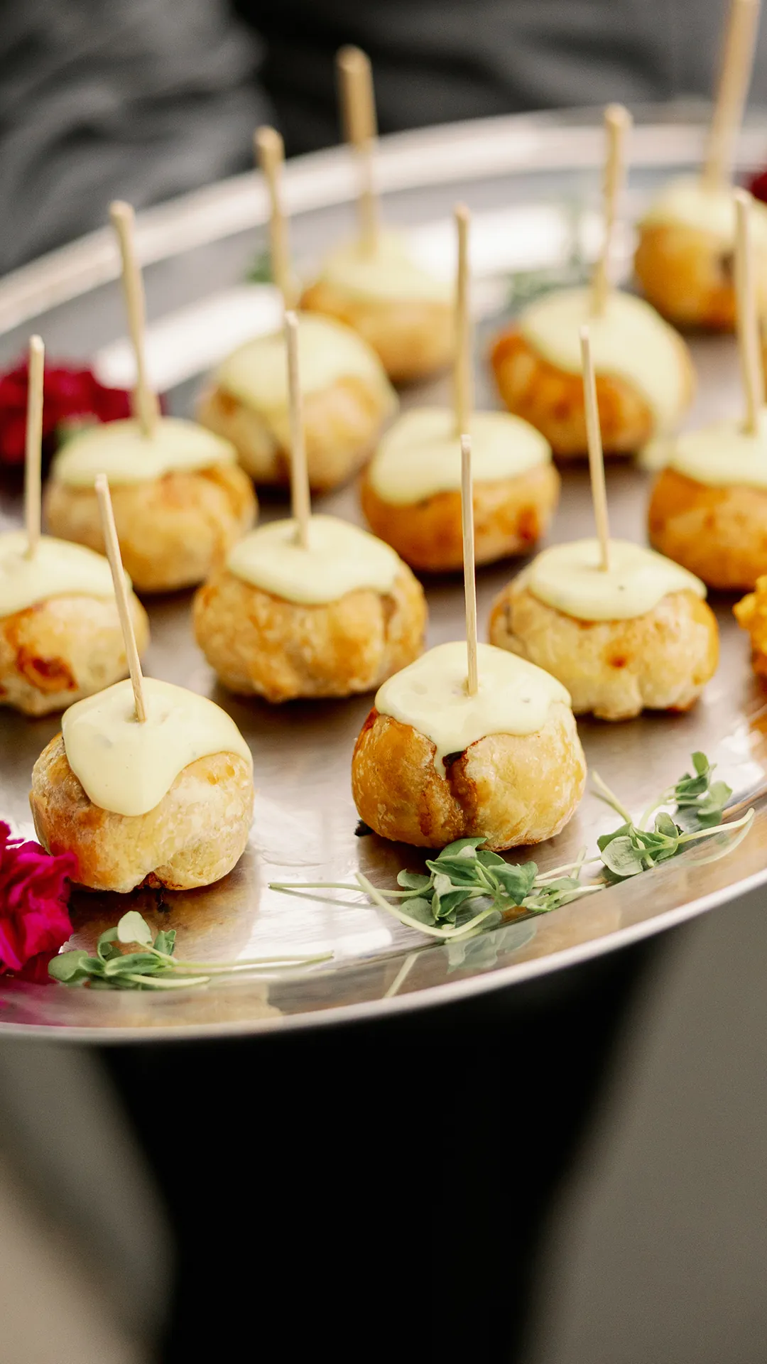 Mini beef Wellingtons topped with béarnaise sauce and cocktail picks on a serving tray