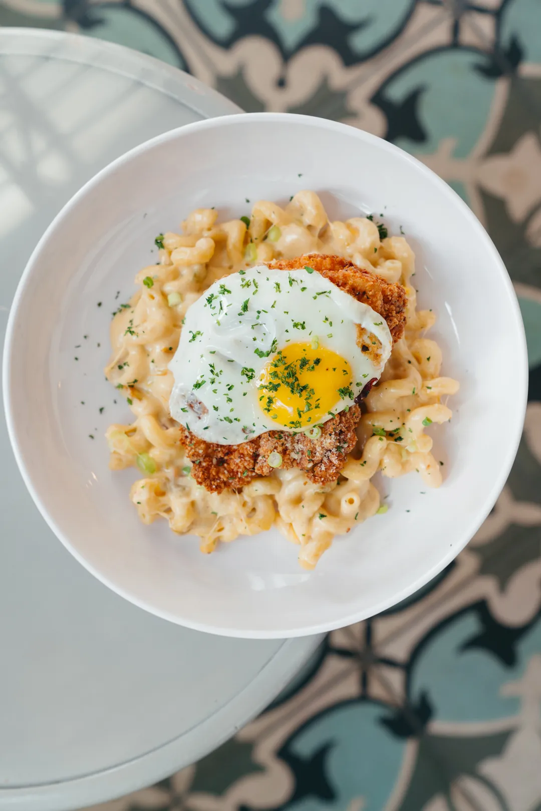 Crispy chicken mac topped with a fried egg, bacon, and green onion