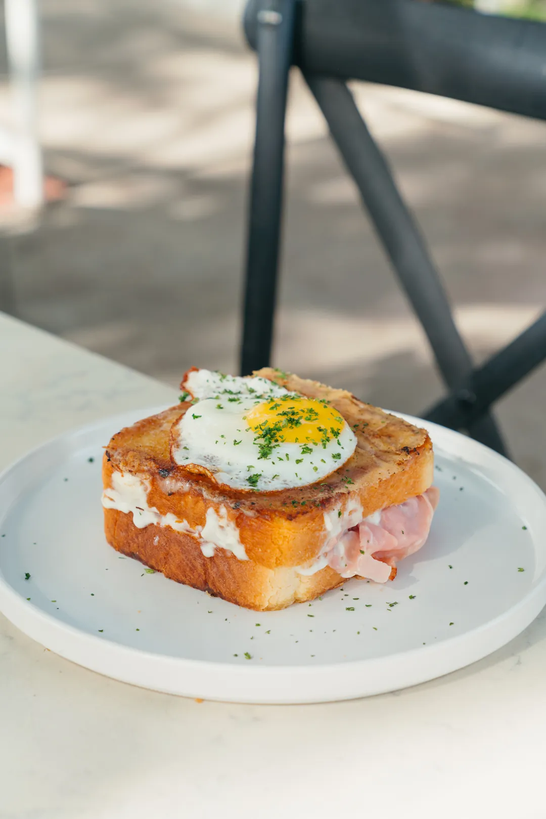 Croque madame topped with Swiss cheese and a sunny-side egg