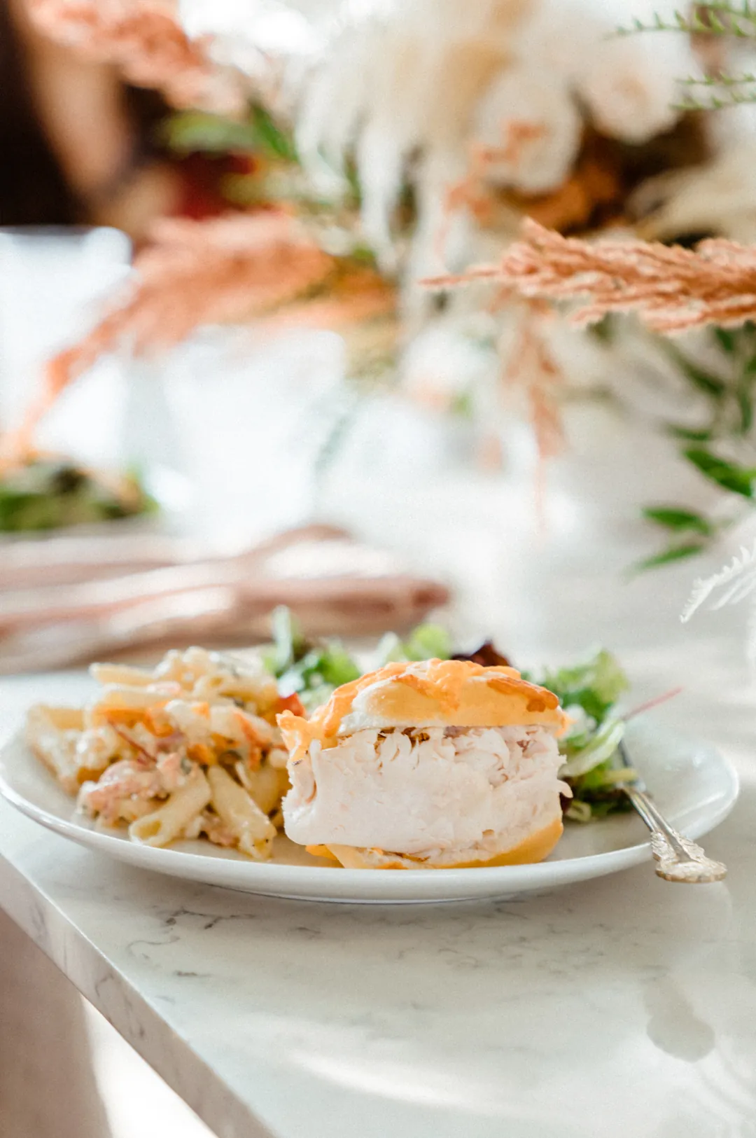 Turkey sandwich with pasta salad and mixed greens on a plate