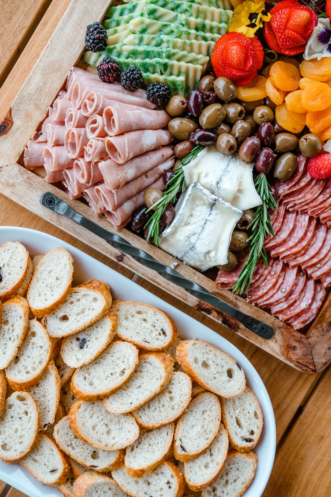 Charcuterie board with cured meats, cheeses, grapes, berries, and sliced bread