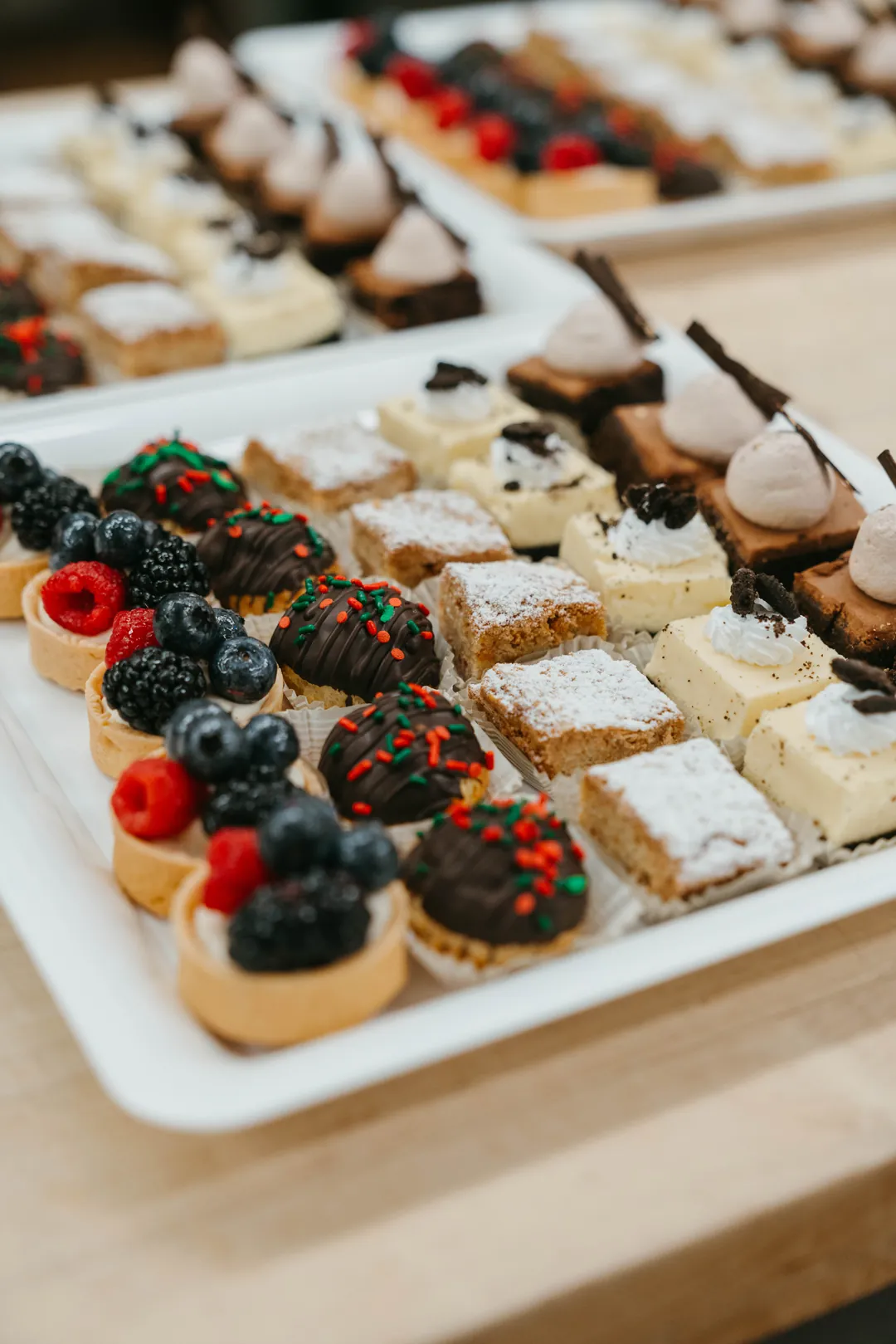Assorted dessert bars and fruit tarts topped with berries