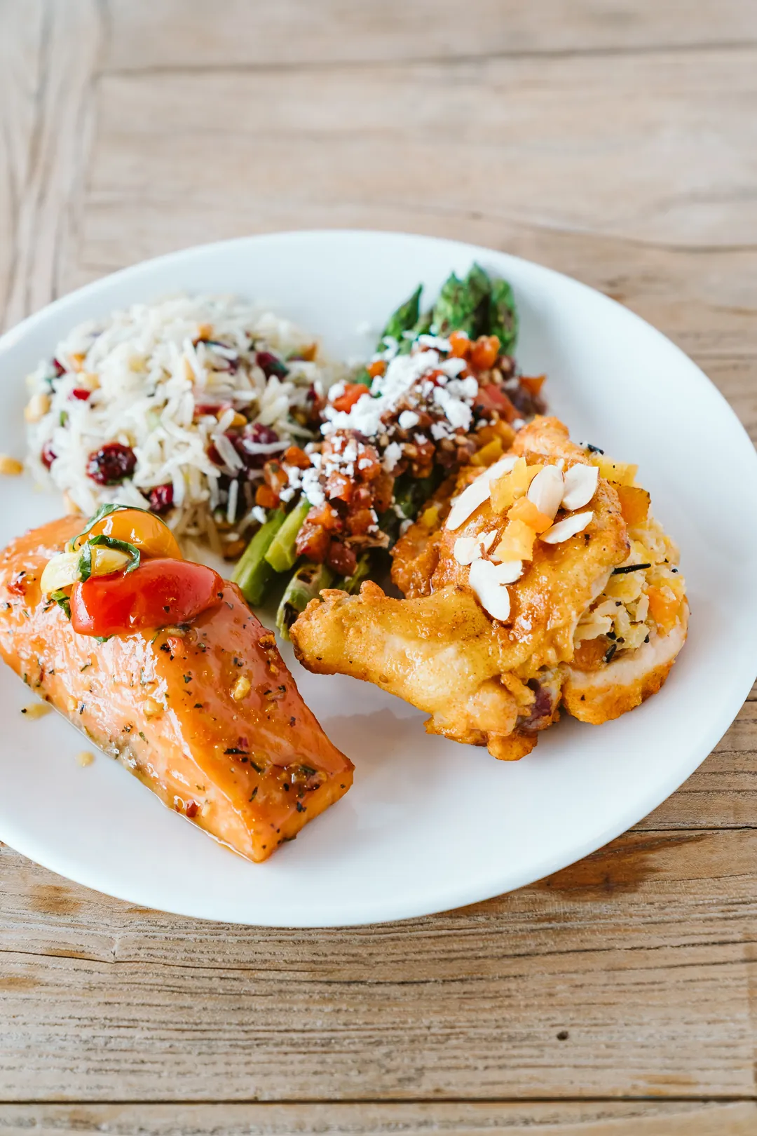 Plate with salmon, rice, roasted vegetables, and a mixed salad