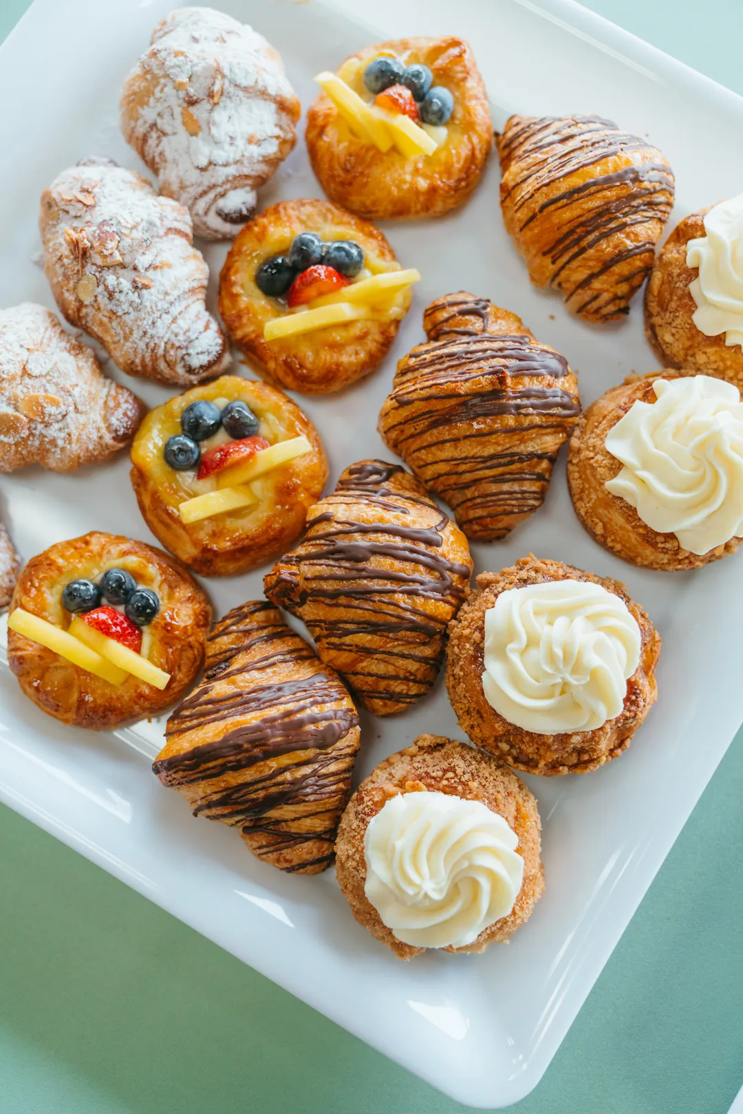 Assorted croissants, fruit danishes, and cream-topped pastries