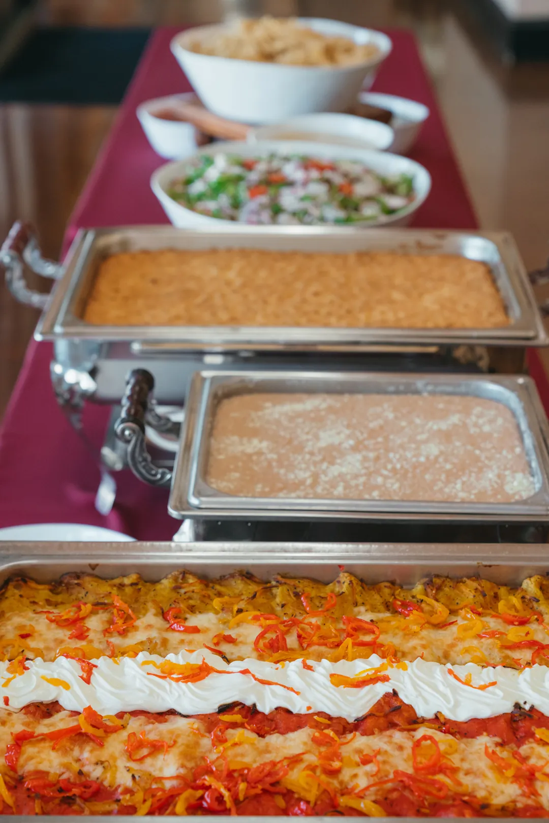 Buffet line with enchiladas, rice, salad, and additional hot dishes