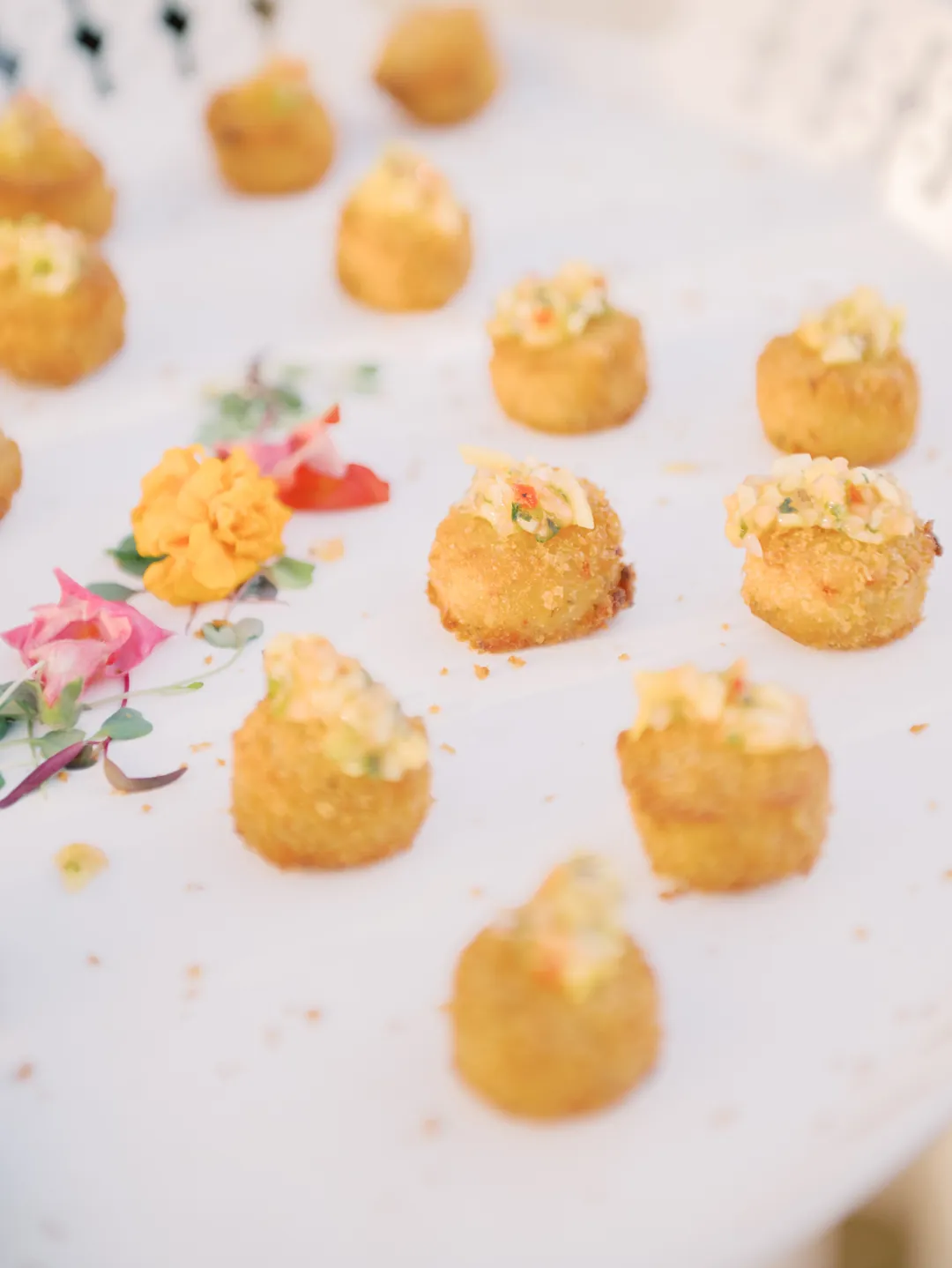 Bite-size crab cakes arranged with edible flowers