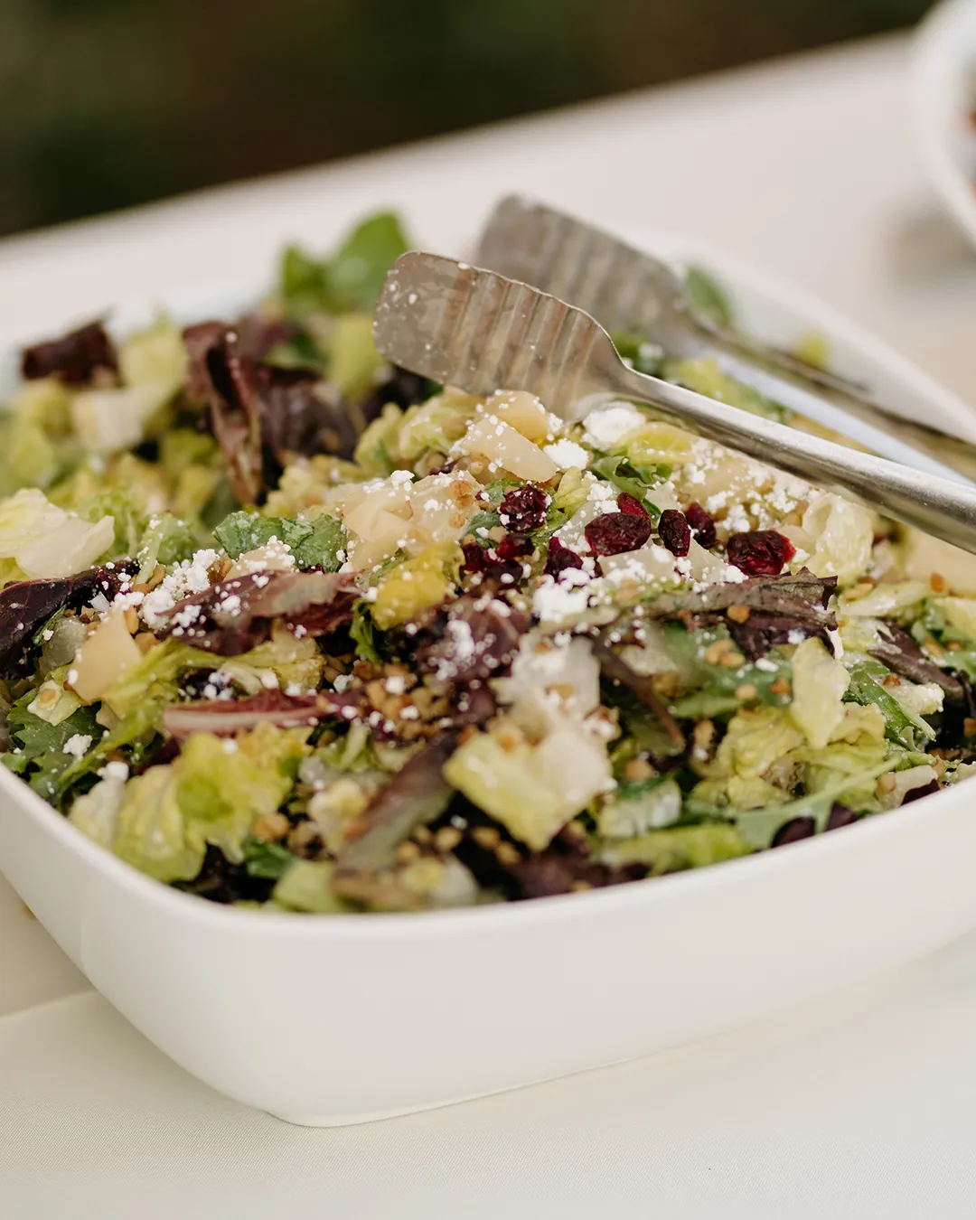 Mixed green salad with cucumbers, dried fruit, and crumbled cheese