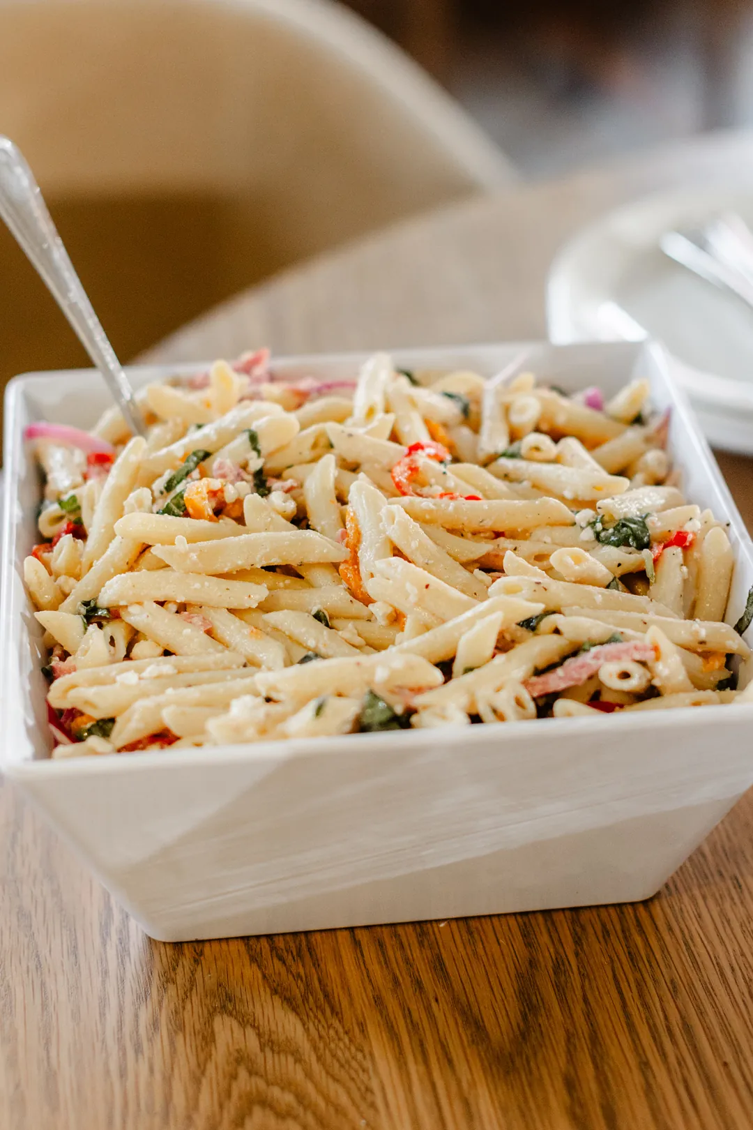 Penne pasta salad with vegetables, herbs, and crumbled cheese