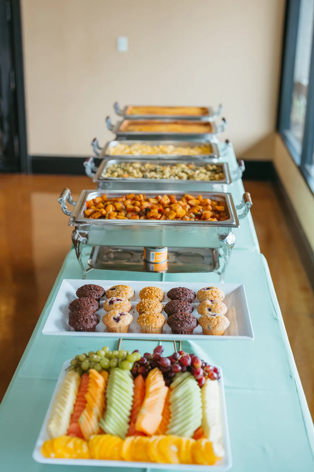 Buffet table with sliced fruit, baked goods, and chafing dishes