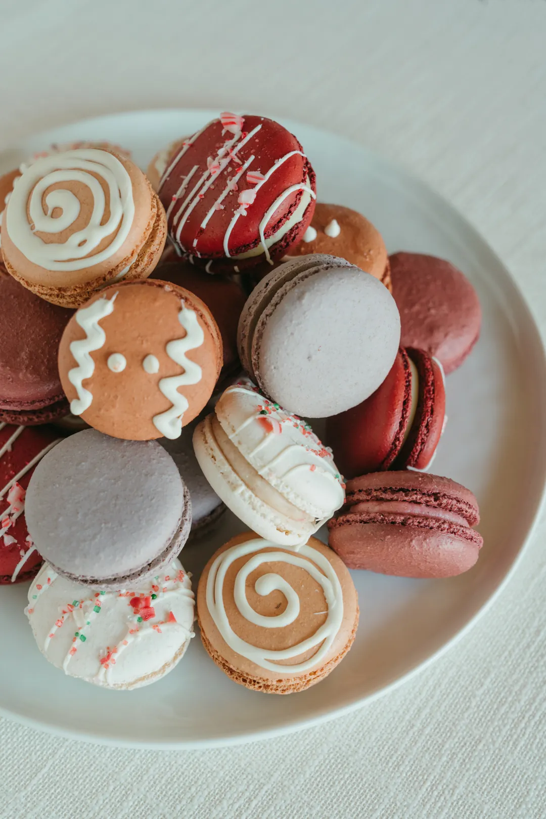 Winter macarons decorated like gingerbread, peppermint, and cinnamon rolls