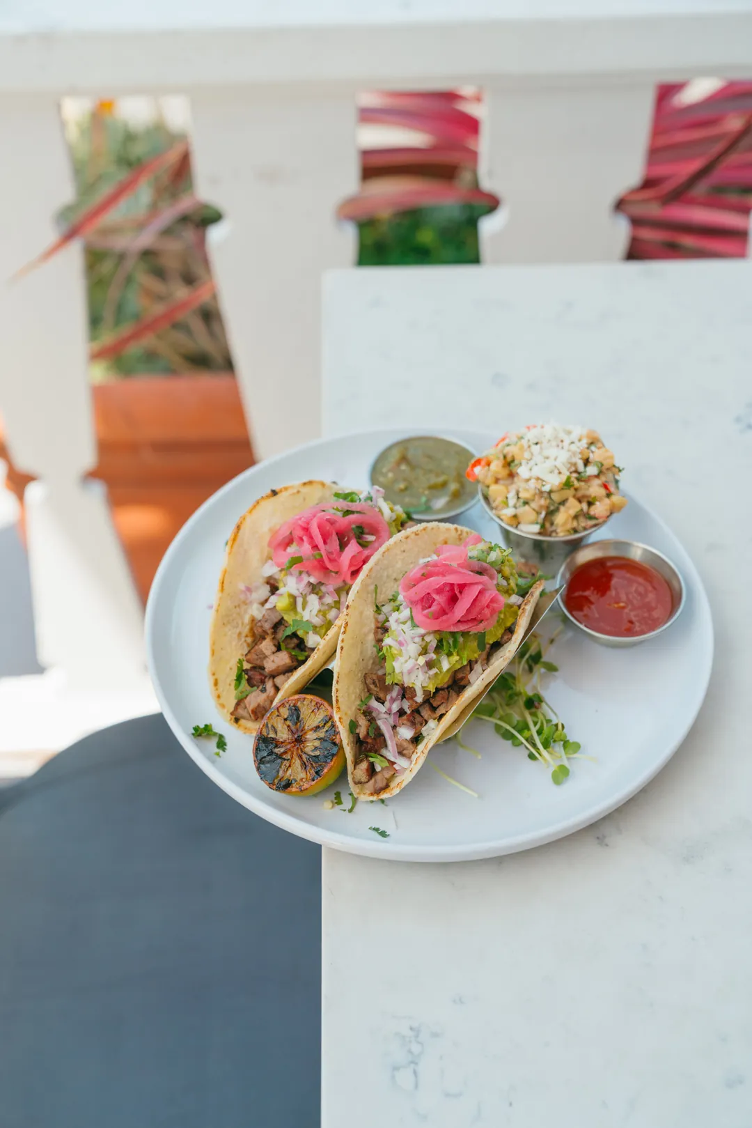 Three steak tacos with salsa and a side of corn salad