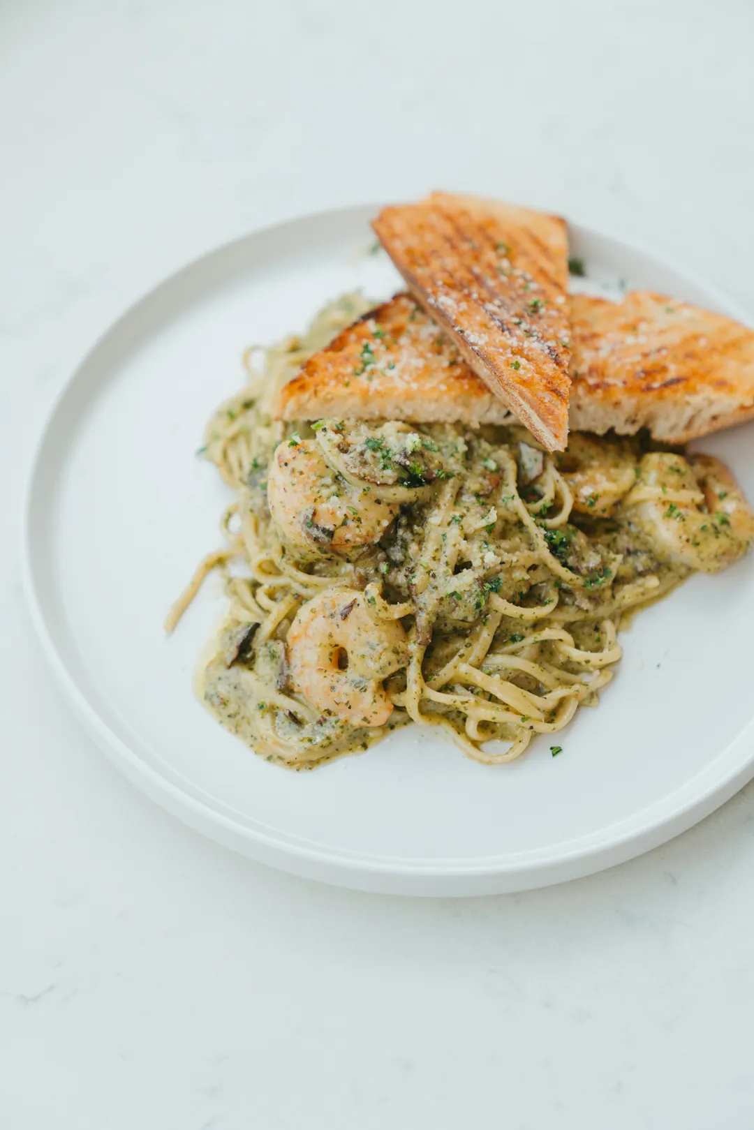 Shrimp and pesto linguine with two slices of toasted bread