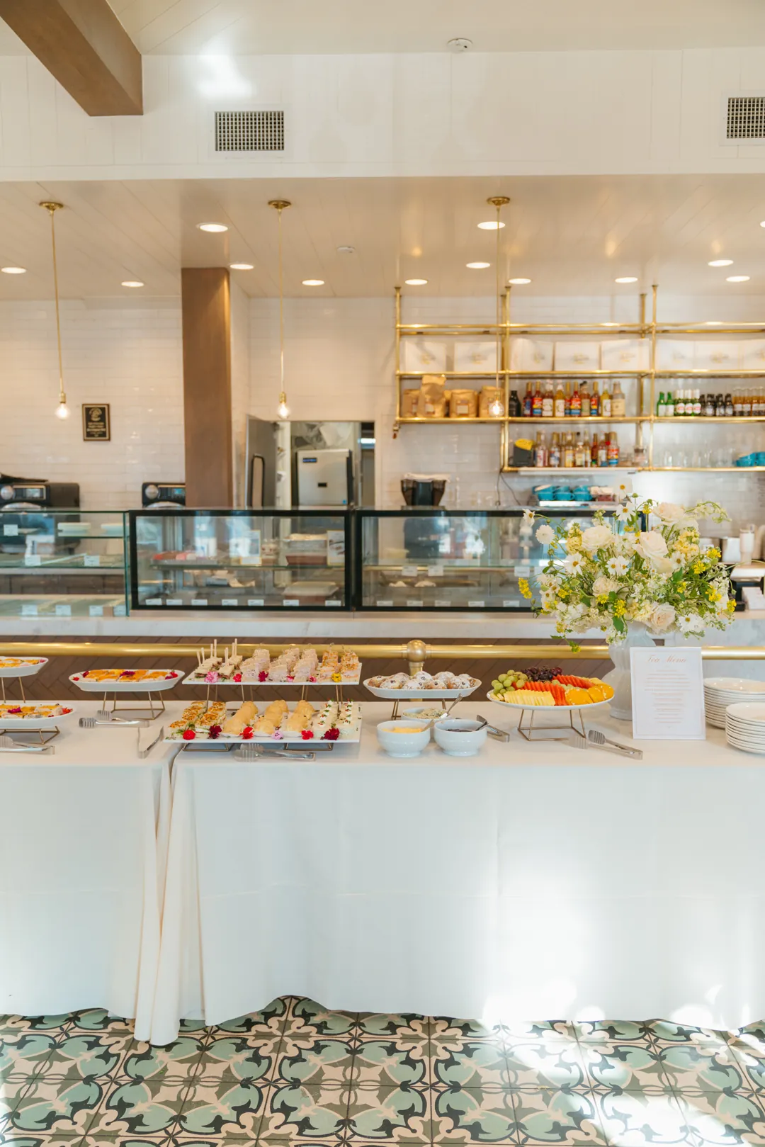 Tea buffet with sandwiches, fruit, pastries and white flowers inside Ellie's Table