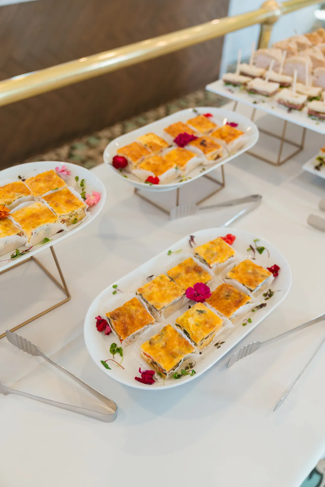Assorted baked quiche squares on white platters