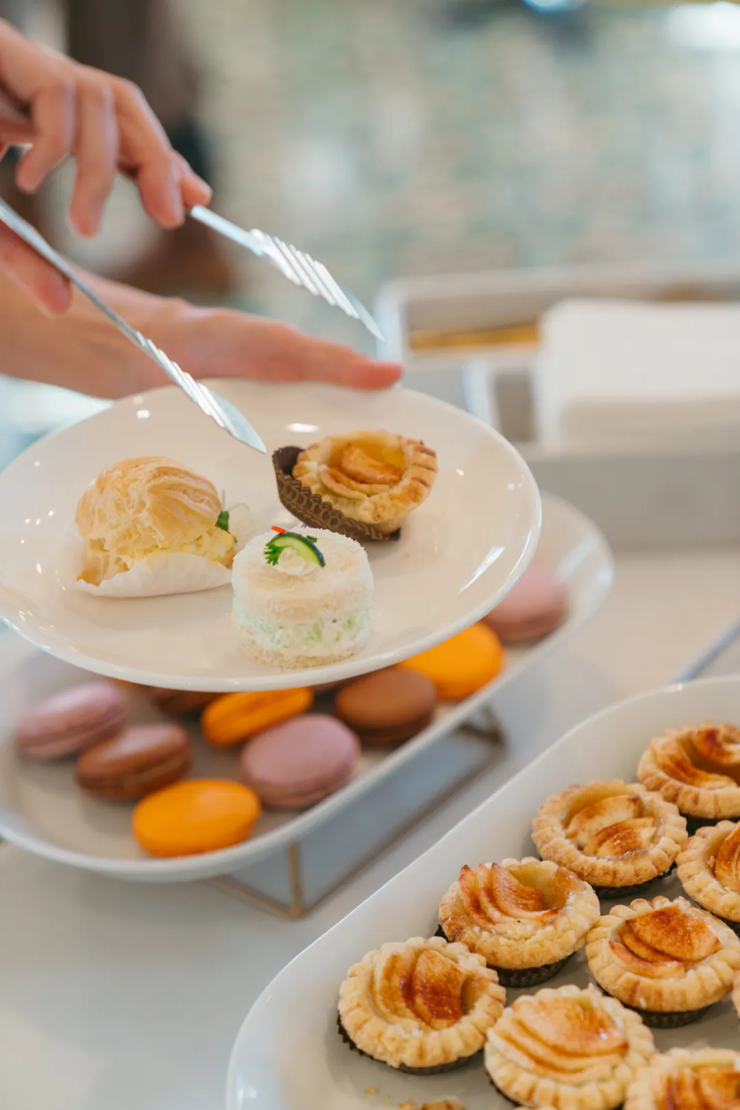 Plate with a pastry puff, cucumber sandwich and apple tart above the buffet