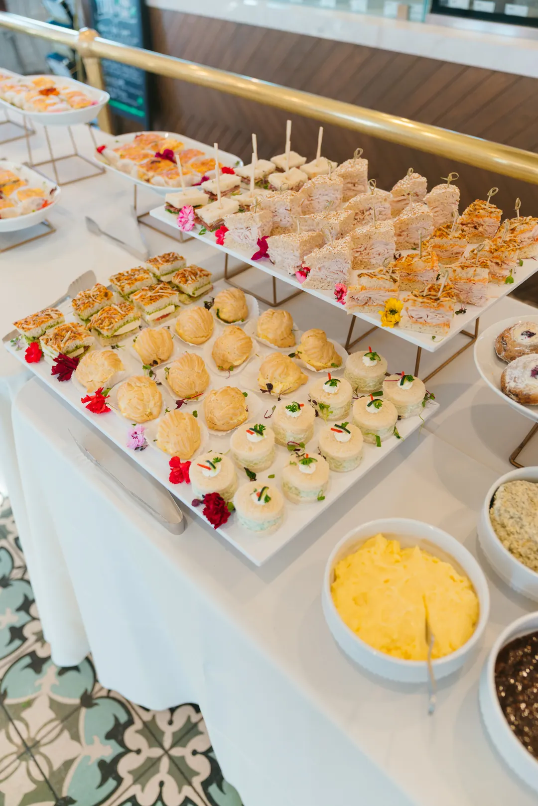 Tiered trays of assorted tea sandwiches beside small bowls of spreads