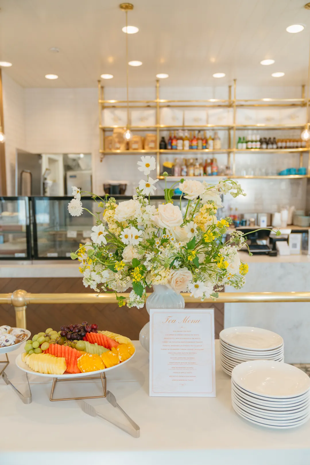 Fruit platter, framed tea menu and white flowers on a buffet table