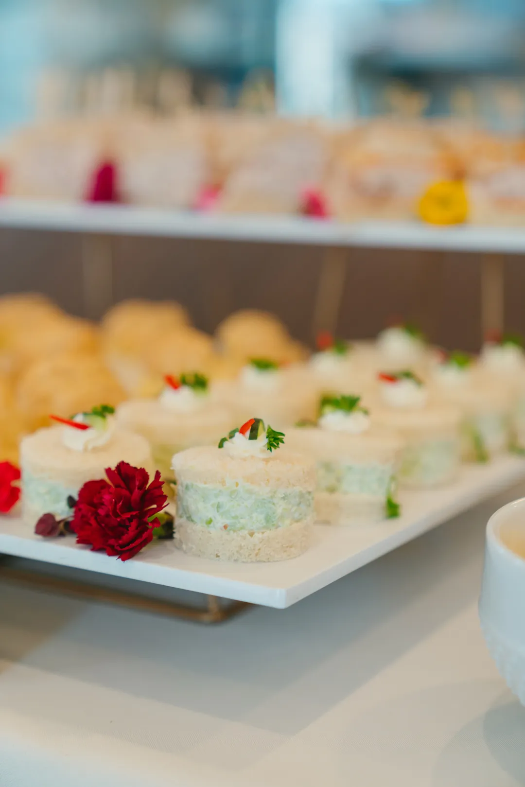 Round cucumber tea sandwiches garnished with herbs and red pepper