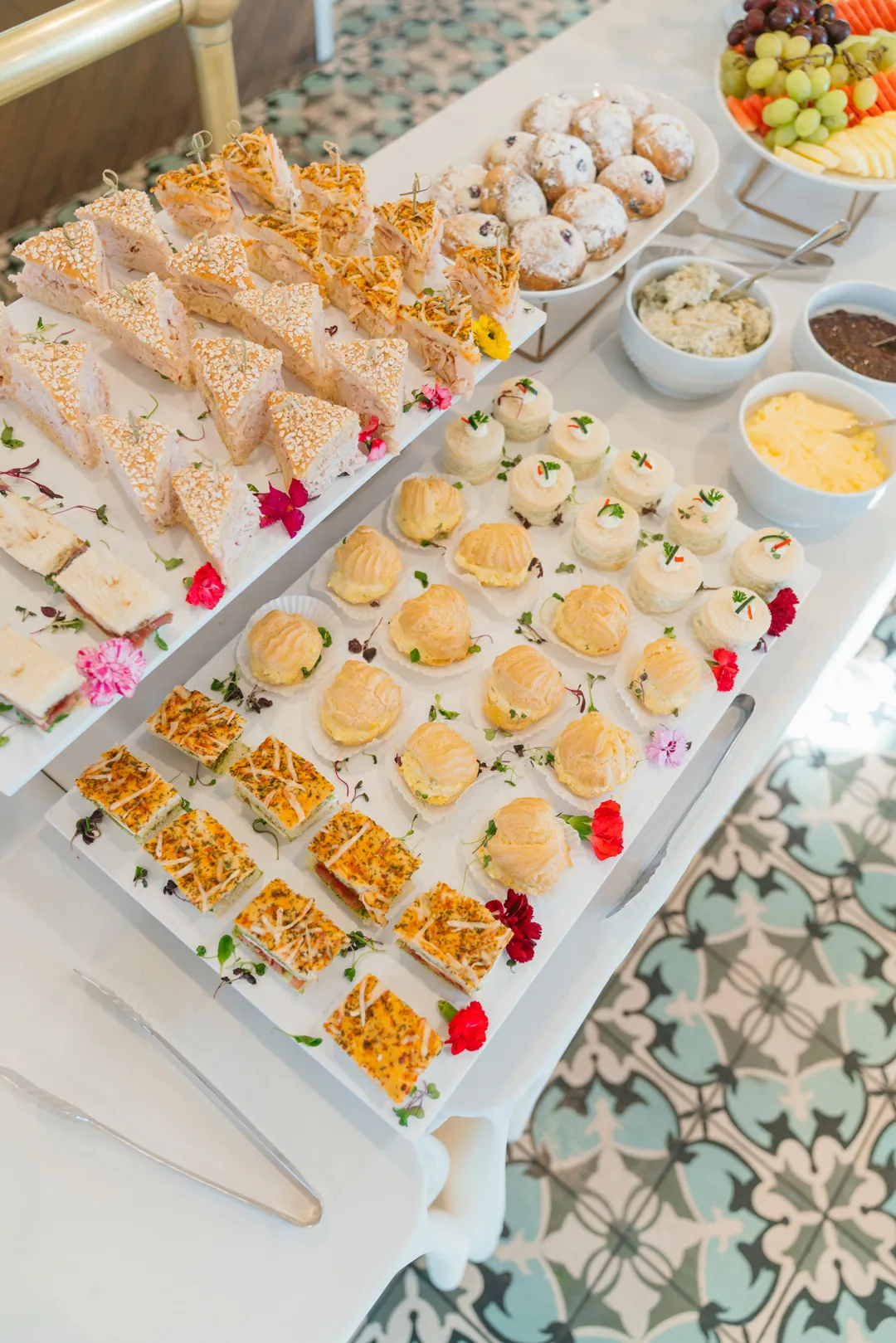 Assorted tea sandwiches, filled pastry puffs, berry pastries and fruit