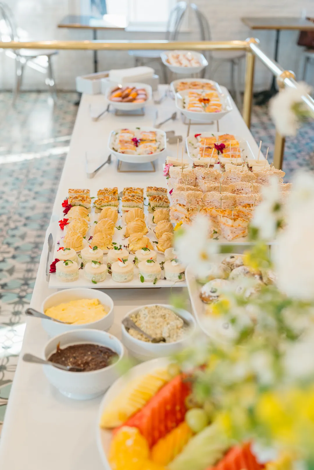 Long tea buffet with sandwiches, pastries, fruit and spreads