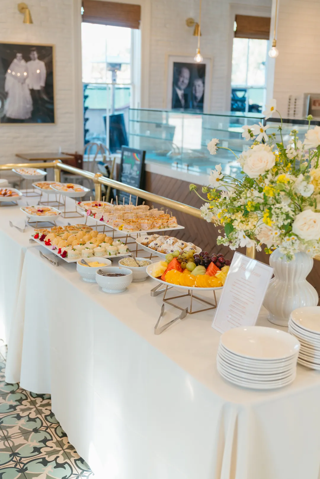 Tea buffet with sandwiches, fruit, pastries and white and yellow flowers