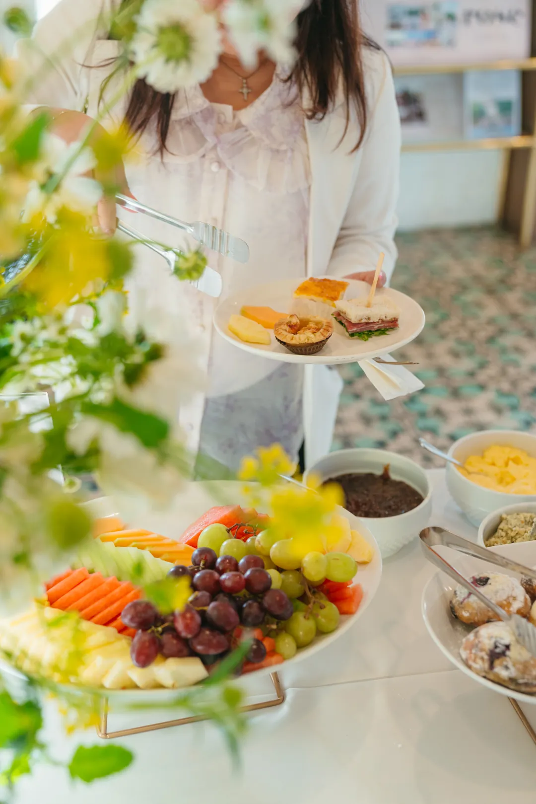 Guest holding a plate beside the fruit and pastry buffet