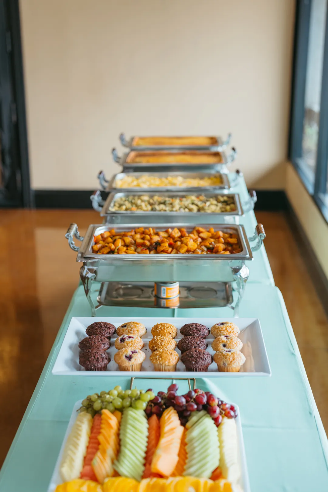 Breakfast buffet with fruit, muffins, potatoes, scrambled eggs and quiche