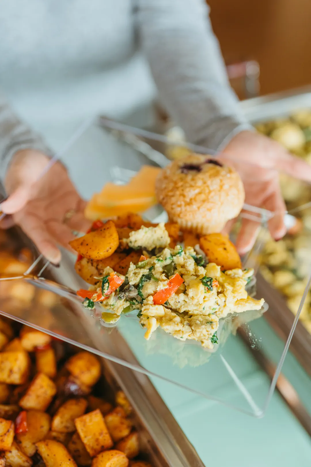 Plate with vegetable scrambled eggs, potatoes, fruit and a berry muffin