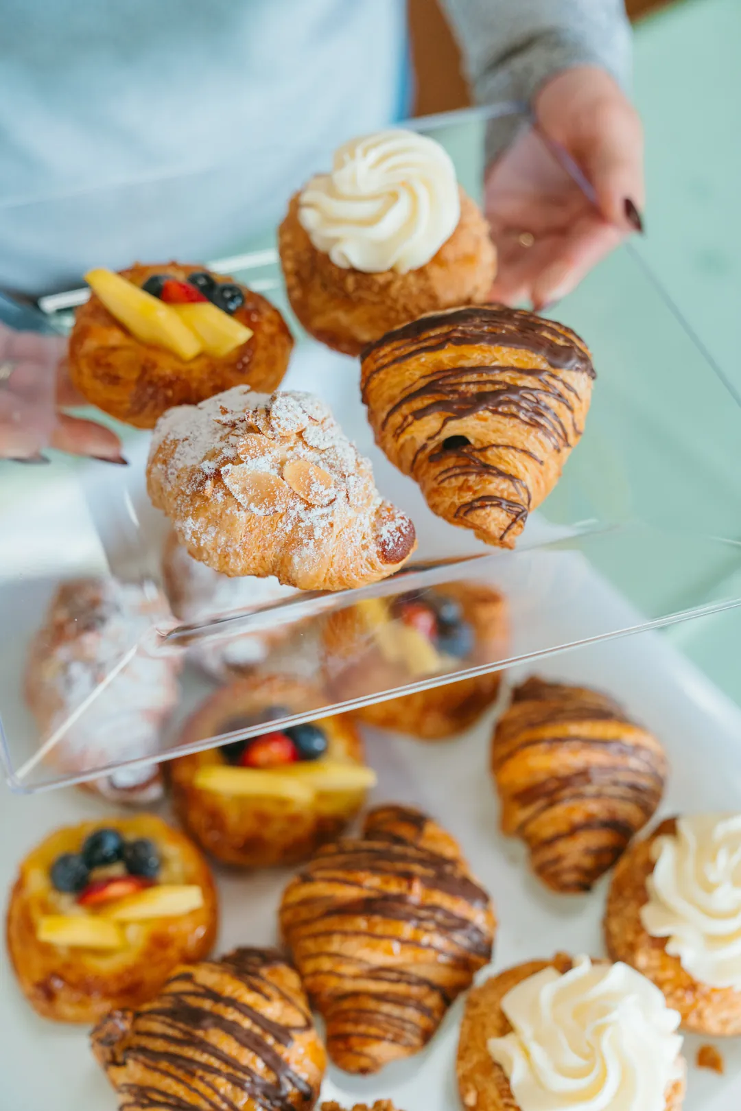 Guest holding four assorted pastries above a pastry tray